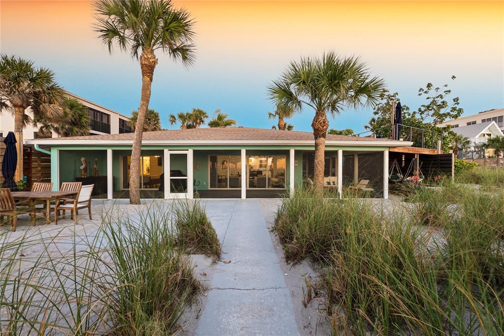 A single-story beach house with a screened porch, palm trees, and a sandy yard — 2630 N BEACH ROAD, ENGLEWOOD, FL
