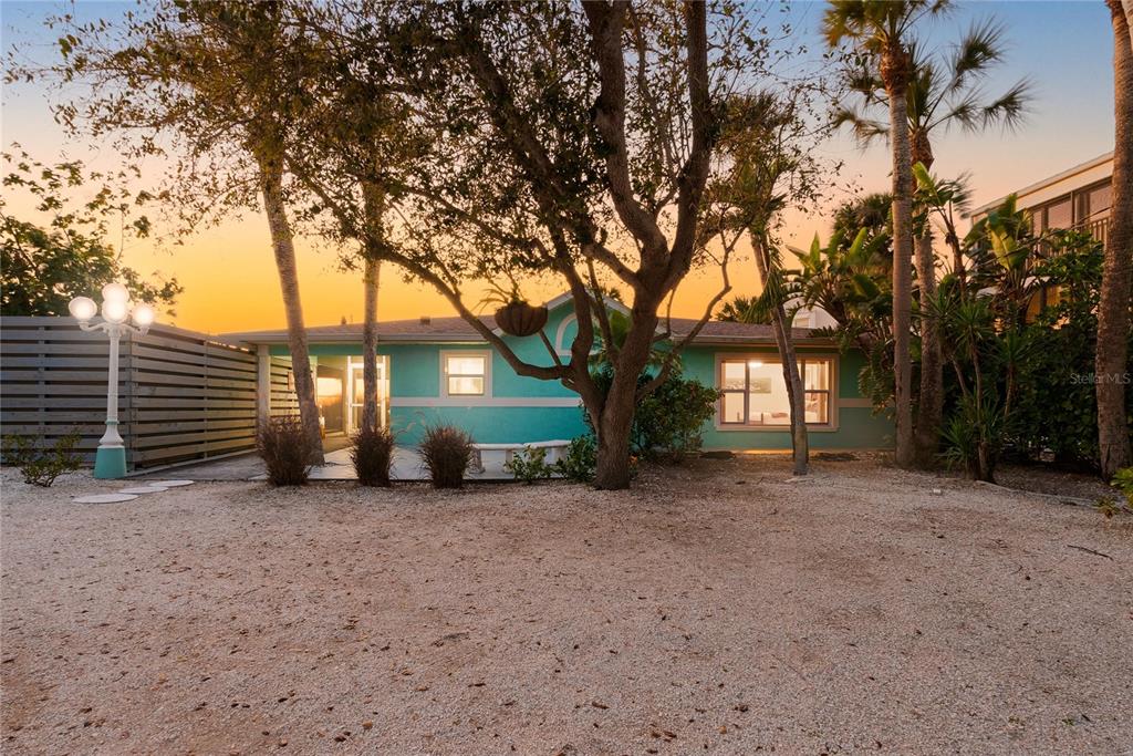 A teal, single-story house sits behind a gravel yard with trees and a lamp post — 2630 N BEACH ROAD, ENGLEWOOD, FL