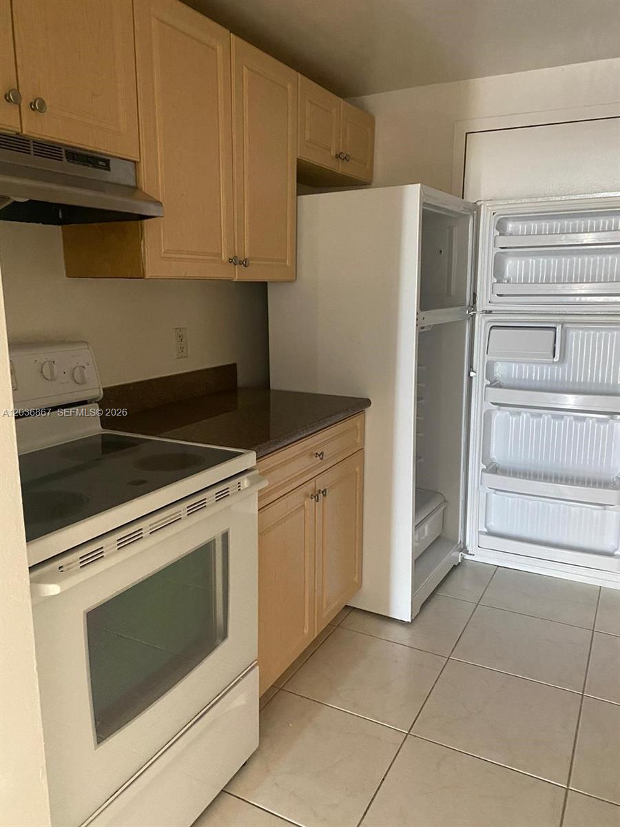 A kitchen features light wood cabinets, a white stove, and a white refrigerator — NORTH MIAMI, FL