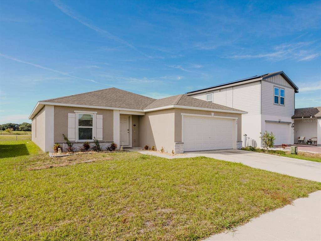 A single-story suburban house with a tan stucco exterior, a two-car garage, and a driveway — 288 TOWNS CIRCLE, HAINES CITY, FL