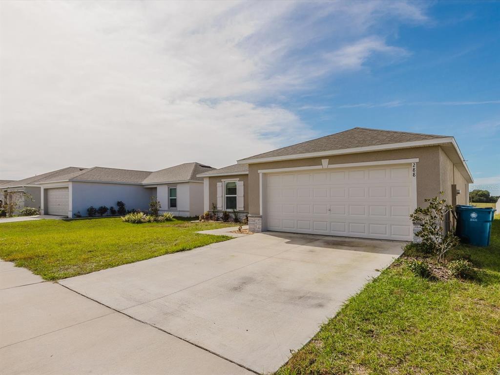 A living room and dining area feature neutral carpet, beige furniture, and a sliding glass door — 288 TOWNS CIRCLE, HAINES CITY, FL