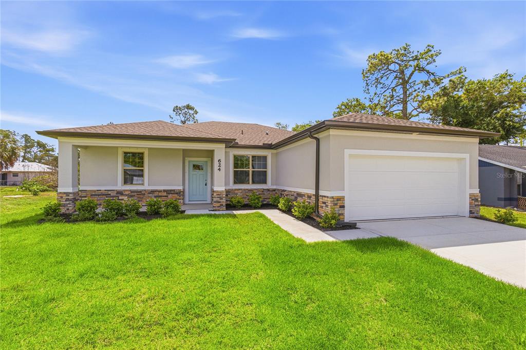 A single-story house with a light blue door, stone veneer accents, and a two-car garage — 2624 ATWATER DRIVE, NORTH PORT, FL