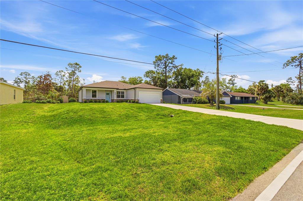 A single-story house with a light-colored exterior and a concrete driveway sits on a lawn — 2624 ATWATER DRIVE, NORTH PORT, FL