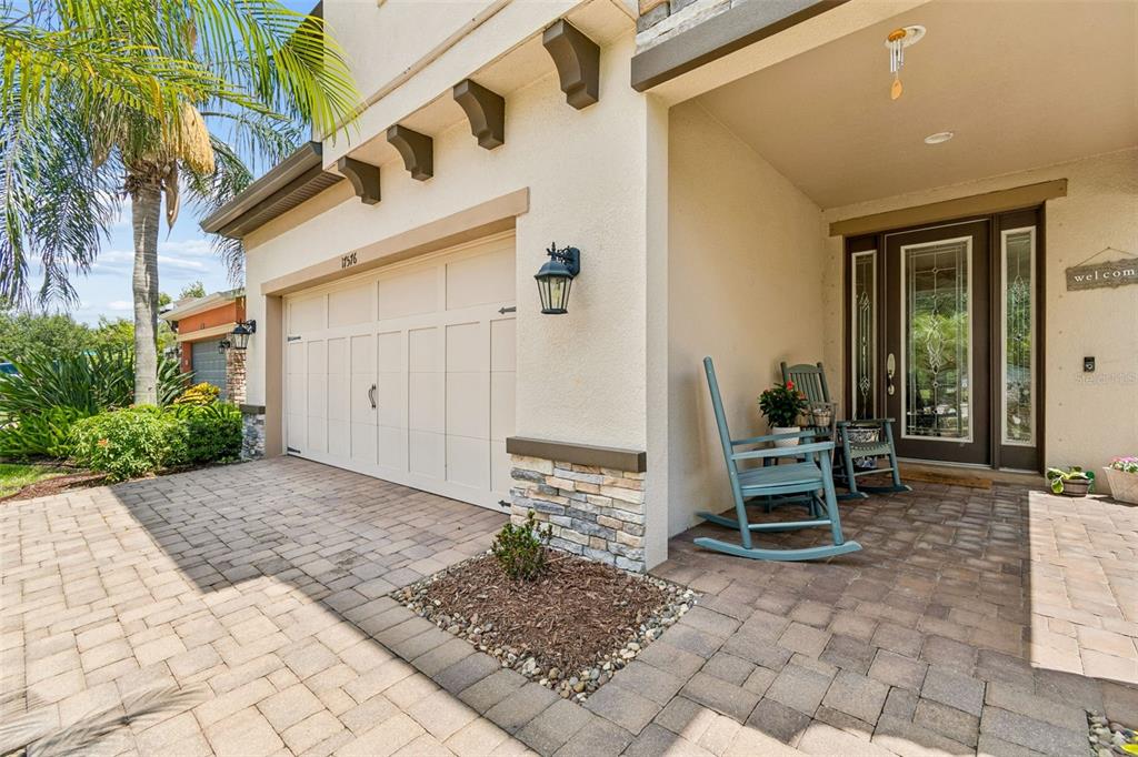 A paved driveway leads to a garage and a covered front porch with two rocking chairs — 17576 TERRAZZO WAY, LAND O LAKES, FL