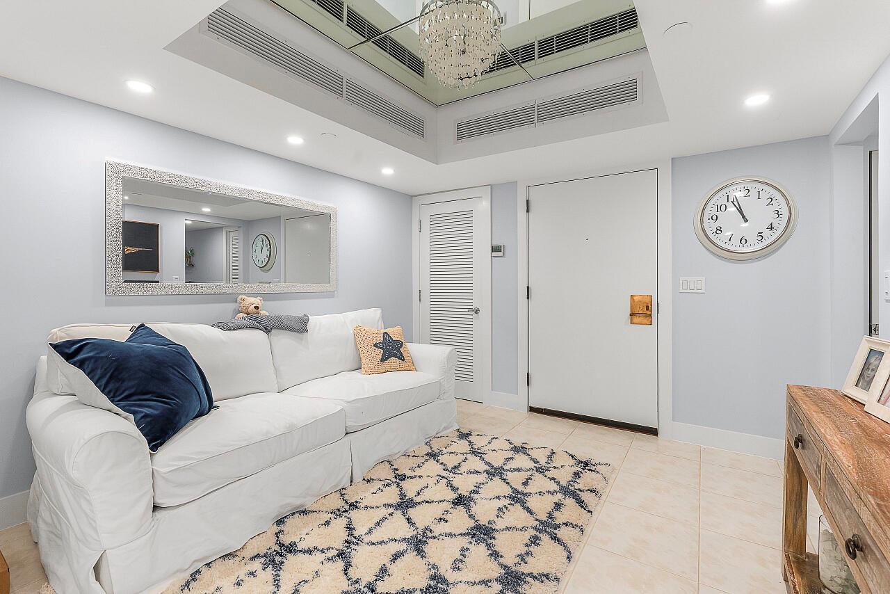 A white sofa sits on a patterned rug in a room with a large wall clock — 100 Lakeshore Drive # 252, North Palm Beach FL 33408, NORTH PALM BEACH, FL