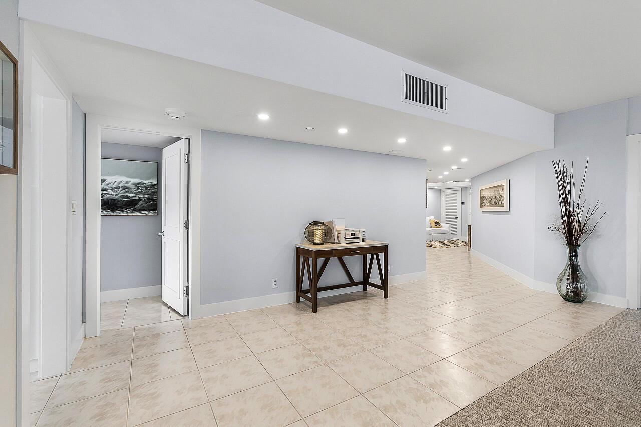 A tiled hallway features a wooden console table, recessed lighting, and a doorway to another room — 100 Lakeshore Drive # 252, North Palm Beach FL 33408, NORTH PALM BEACH, FL