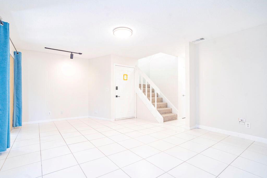 An empty room with white tile flooring, a white front door, and a staircase — 950 S Kanner Highway # 124, Stuart FL 34994, STUART, FL