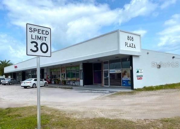A white commercial plaza building with a speed limit sign in the foreground — 814 COURT STREET, CLEARWATER, FL