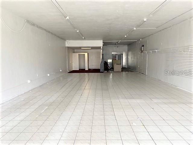 An empty commercial space features white tiled floors, white walls, and overhead fluorescent lighting — 814 COURT STREET, CLEARWATER, FL