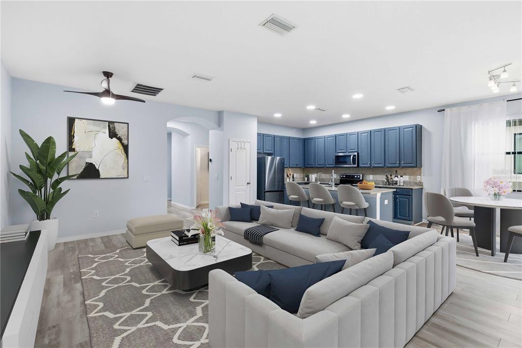 This open-concept living room and kitchen features blue cabinetry, a sectional sofa, and light flooring — 11415 BLUE CRANE STREET, RIVERVIEW, FL