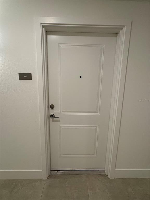 A multi-story apartment building exterior features gray siding, white stucco walls, and a glass entrance — 5579 MILLENIA PARK BOULEVARD UNIT 506, ORLANDO, FL