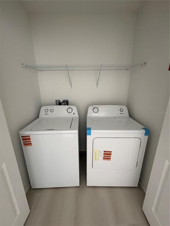 A laundry closet contains a white top-loading washing machine and a matching electric dryer — 5579 MILLENIA PARK BOULEVARD UNIT 506, ORLANDO, FL