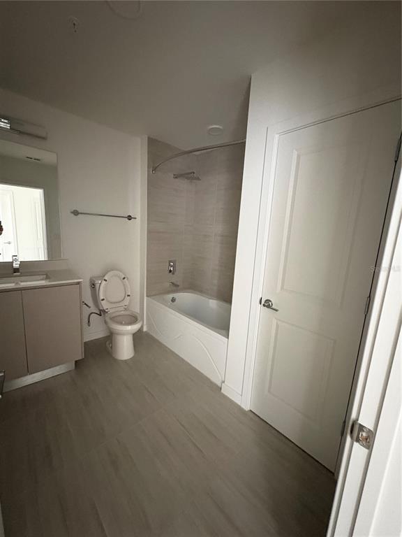 A bathroom features a vanity, toilet, and a tiled bathtub-shower combination with light-colored flooring — 5579 MILLENIA PARK BOULEVARD UNIT 506, ORLANDO, FL