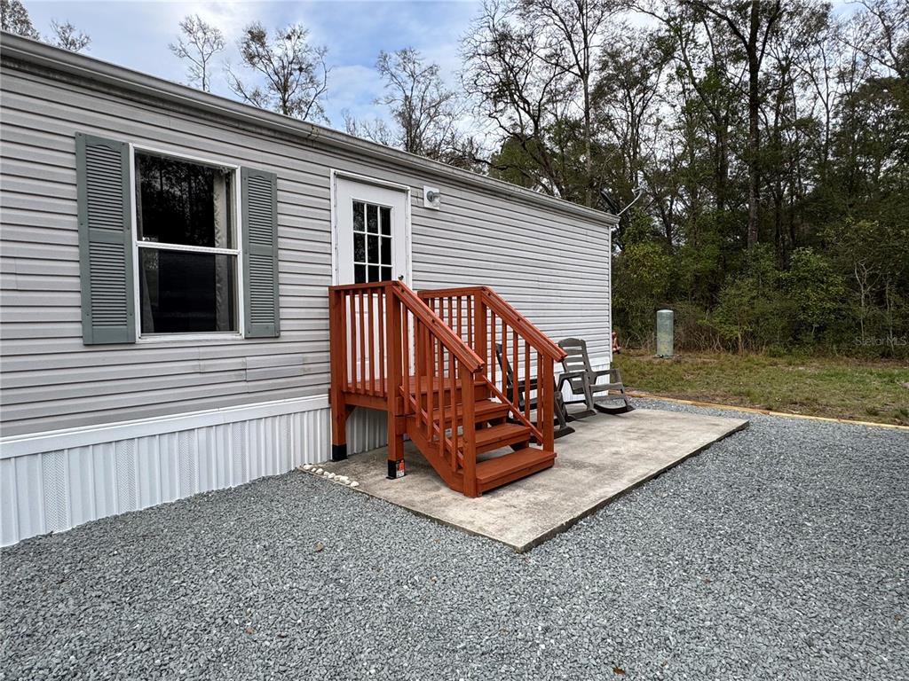 A gray mobile home exterior features a wooden staircase leading to a white door — 4317 284TH STREET, BRANFORD, FL