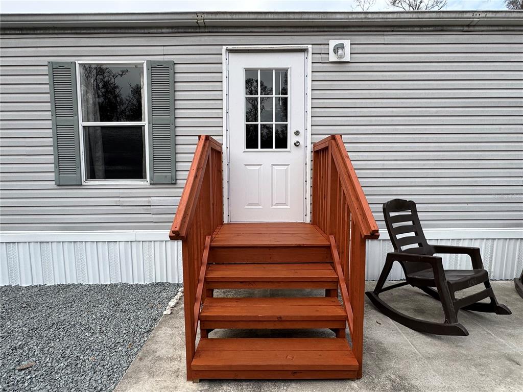 A wooden staircase leads to the white front door of a gray mobile home — 4317 284TH STREET, BRANFORD, FL