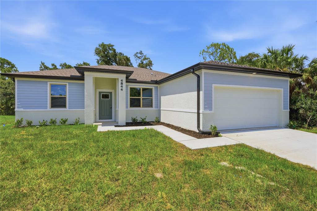 A single-story house with light blue siding, white stucco, and a two-car garage — 4844 FLINT DRIVE, NORTH PORT, FL