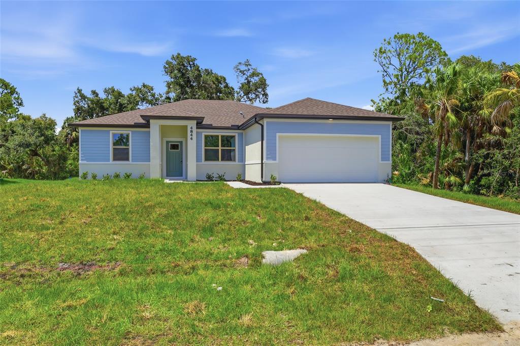 A single-story house with blue siding, a white garage door, and a concrete driveway — 4844 FLINT DRIVE, NORTH PORT, FL