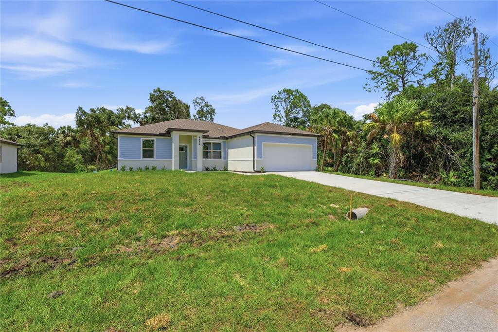 A single-story house with light blue siding and a concrete driveway sits on a lawn — 4844 FLINT DRIVE, NORTH PORT, FL