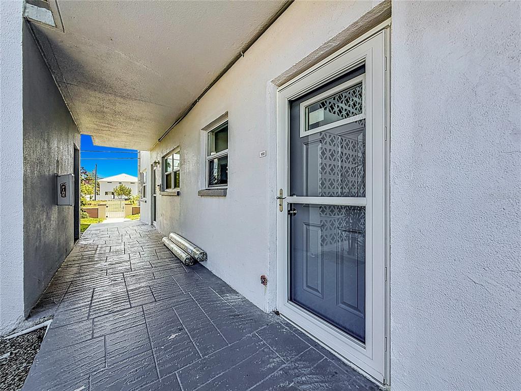 A covered outdoor walkway leads to a gray front door with a screen door — 3018 59TH STREET S UNIT 102, GULFPORT, FL