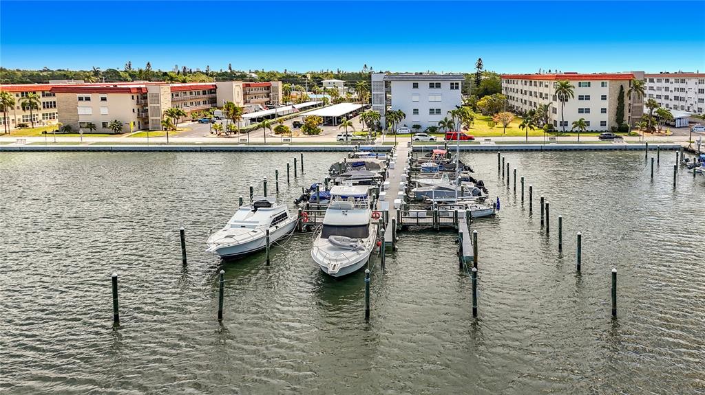 An aerial view shows a marina with several boats docked at a pier near apartment buildings — 3018 59TH STREET S UNIT 102, GULFPORT, FL