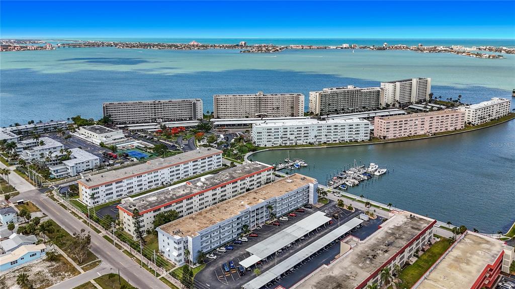 An aerial view shows multiple multi-story apartment buildings situated along a waterfront with a marina — 3018 59TH STREET S UNIT 102, GULFPORT, FL