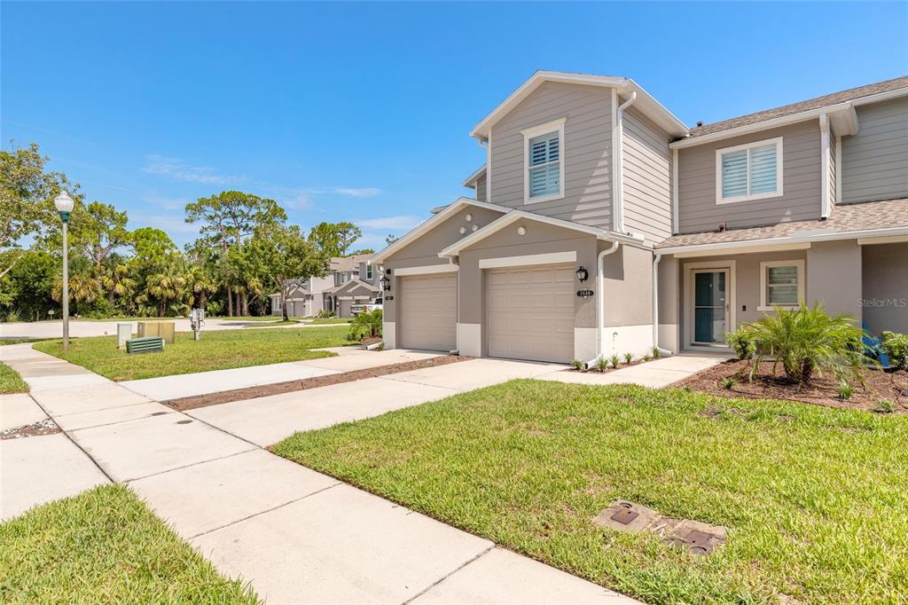 A two-story townhouse exterior features a two-car garage, beige siding, and a concrete driveway — 2669 SICILY DRIVE, NEW SMYRNA BEACH, FL