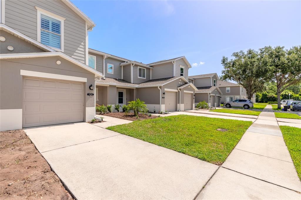 A row of two-story townhomes with attached garages, concrete driveways, and a shared front lawn — 2669 SICILY DRIVE, NEW SMYRNA BEACH, FL