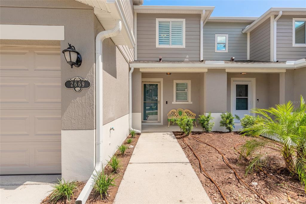 A view of the exterior of a two-story townhouse with a concrete walkway and garage — 2669 SICILY DRIVE, NEW SMYRNA BEACH, FL
