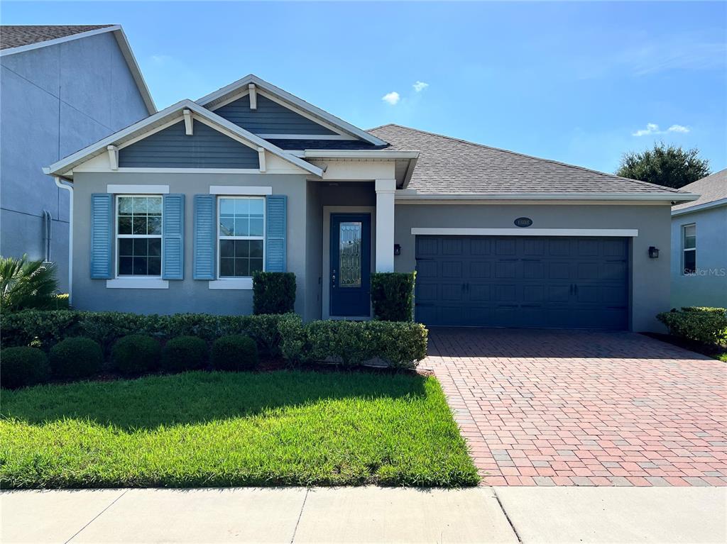 A single-story house with a gray exterior, blue shutters, and a brick-paved driveway — 1808 WESTERN TRAILWAY DRIVE, WINTER GARDEN, FL
