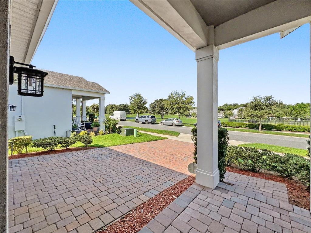 A paved patio area sits beneath a covered porch with a white support column — 1808 WESTERN TRAILWAY DRIVE, WINTER GARDEN, FL
