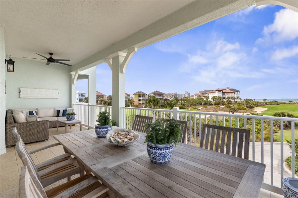 A covered balcony features a wooden dining set, wicker lounge seating, and a coastal view — 400 CINNAMON BEACH WAY UNIT 335, PALM COAST, FL