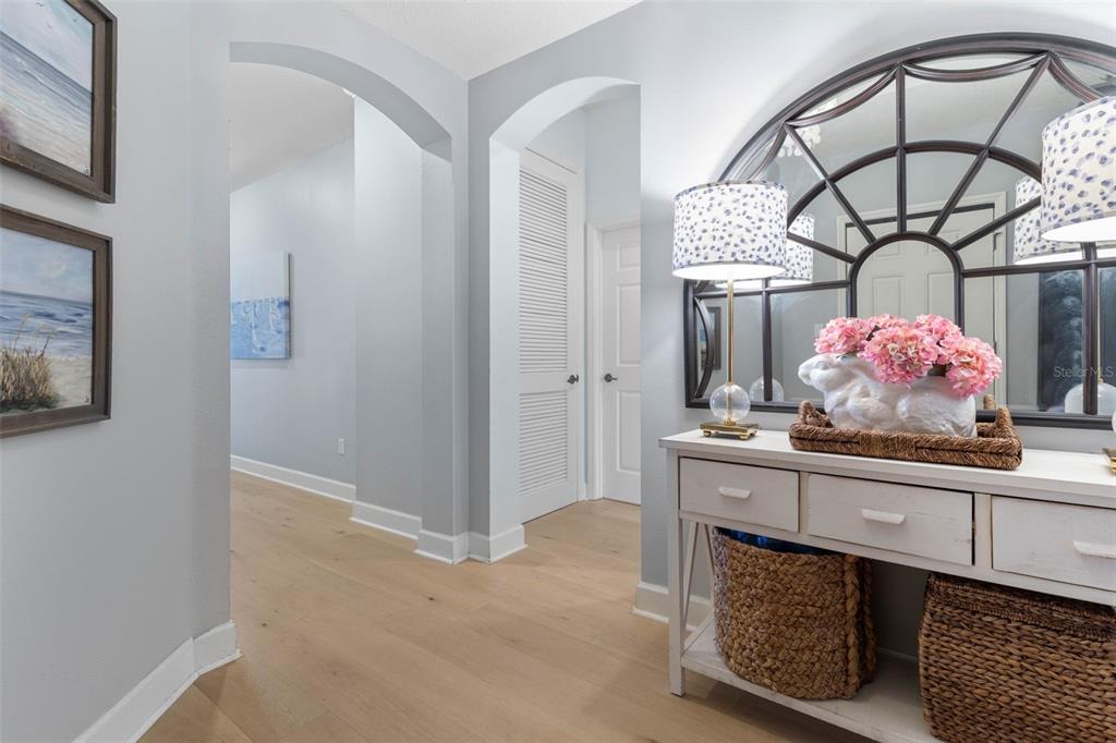 A hallway features light wood floors, arched doorways, a white console table, and wall art — 400 CINNAMON BEACH WAY UNIT 335, PALM COAST, FL
