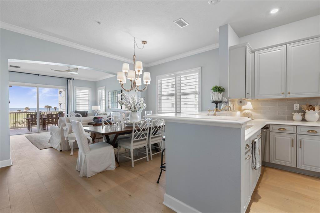 A bright kitchen and dining area features light wood floors, gray cabinetry, and ocean views — 400 CINNAMON BEACH WAY UNIT 335, PALM COAST, FL
