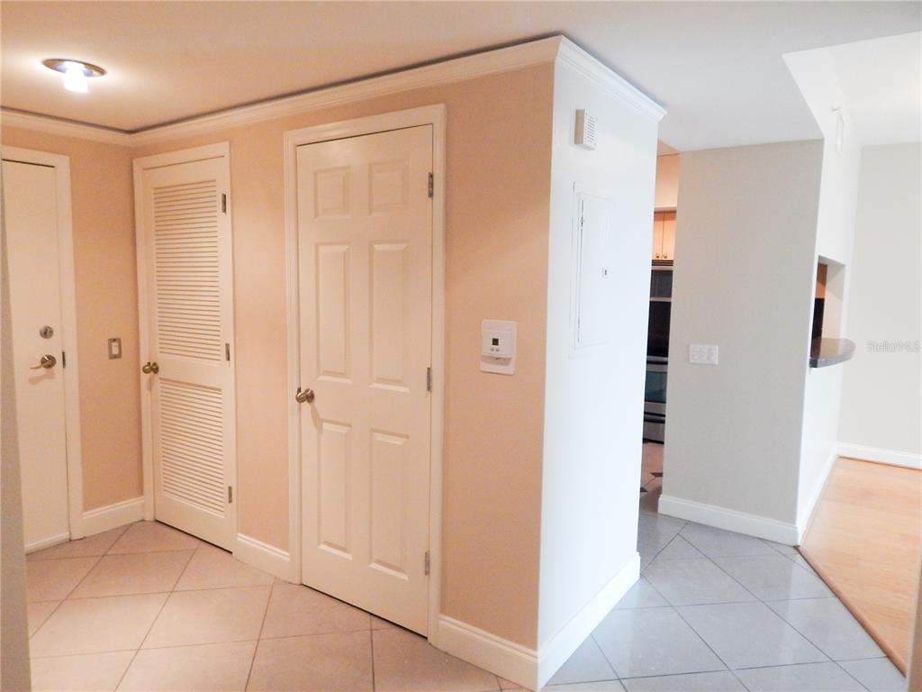 An interior hallway features tiled floors, beige walls, and three white doors — 322 E CENTRAL BOULEVARD UNIT 1104, ORLANDO, FL