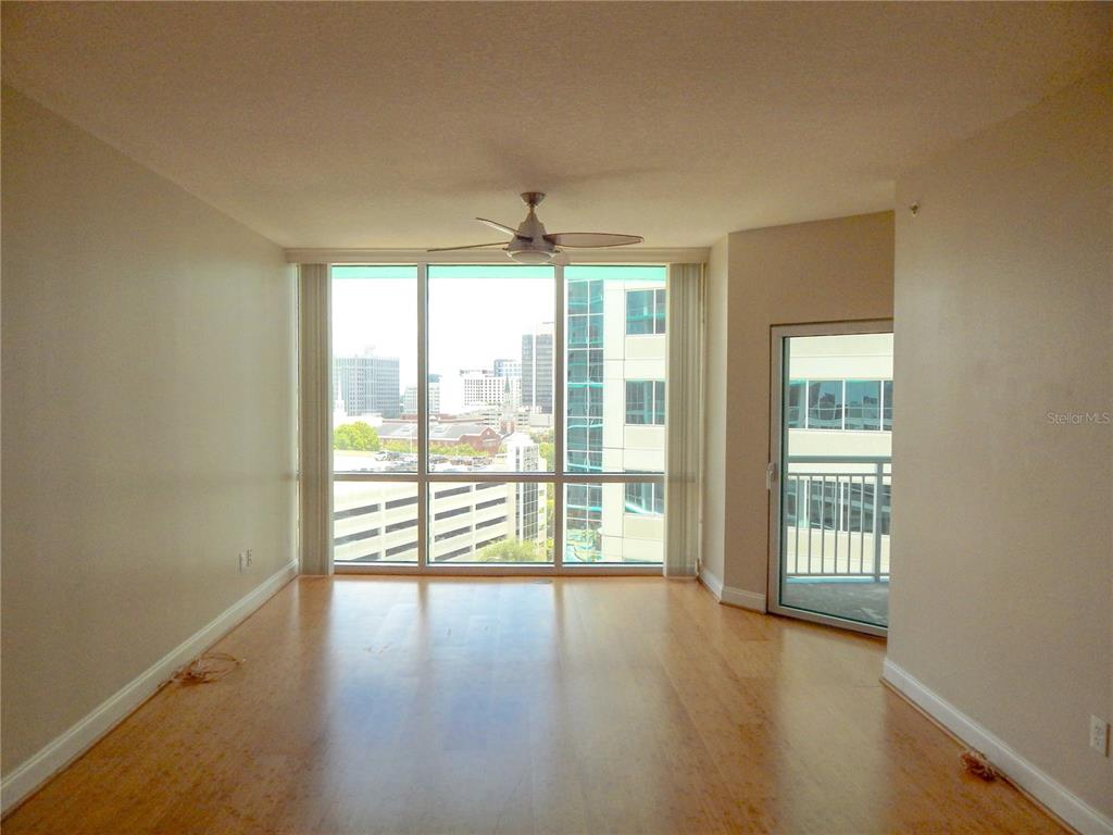 An empty room with hardwood floors, a ceiling fan, floor-to-ceiling windows, and a balcony door — 322 E CENTRAL BOULEVARD UNIT 1104, ORLANDO, FL