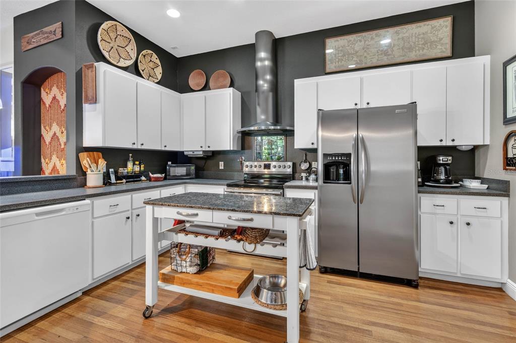 A kitchen features white cabinets, dark countertops, a central island, and stainless steel appliances — 13189 JESSICA DRIVE, SPRING HILL, FL