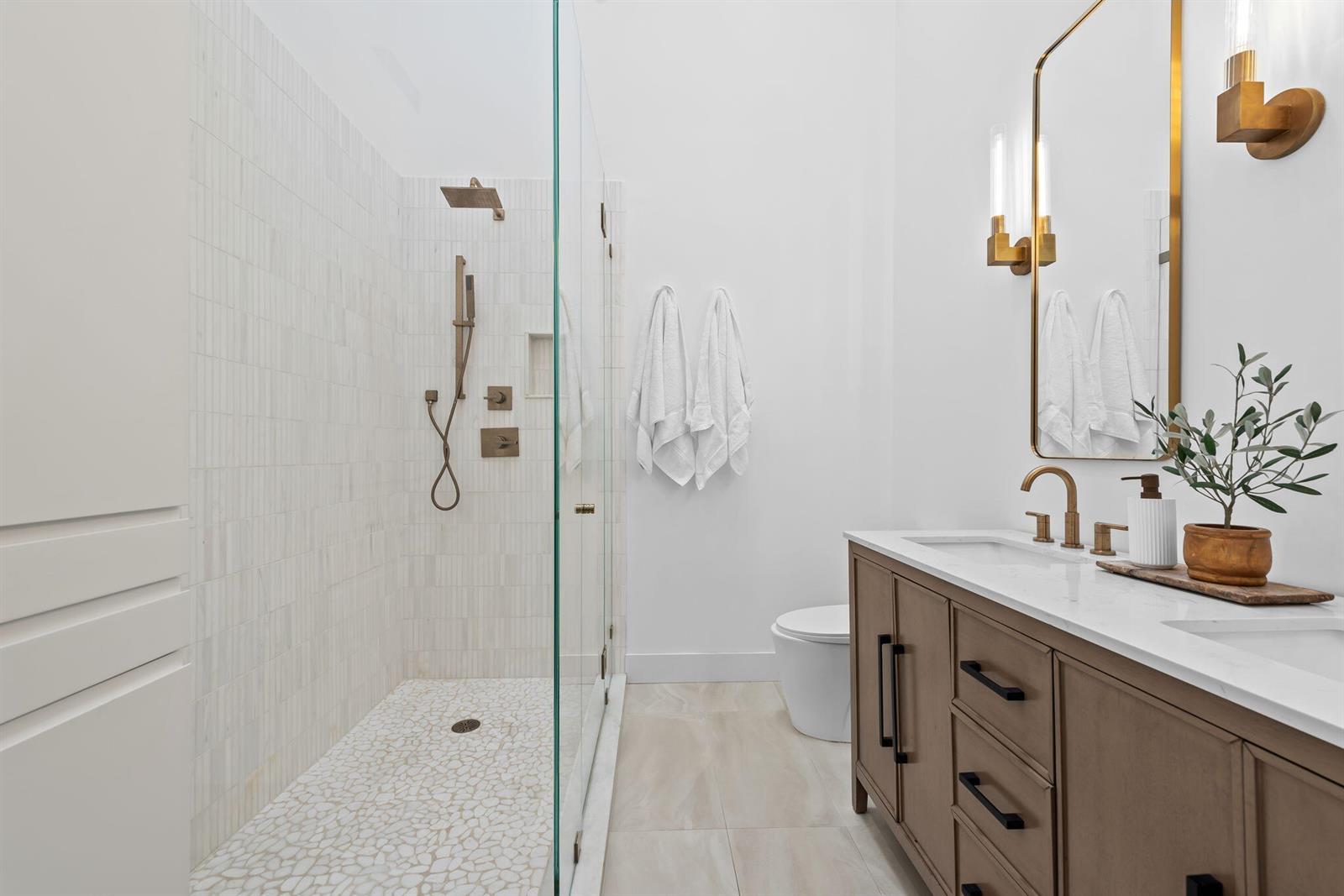 A modern bathroom features a glass-enclosed shower, a double vanity, and brass fixtures — 2930 Florida Boulevard, Delray Beach FL 33483, DELRAY BEACH, FL