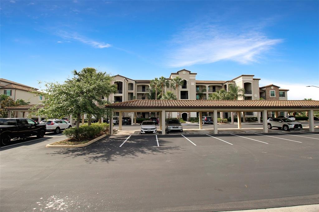 A multi-story apartment building with a covered parking structure in the foreground — 17006 VARDON TERRACE UNIT 406, BRADENTON, FL