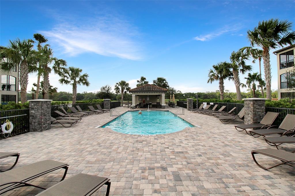 An outdoor swimming pool surrounded by lounge chairs, stone pillars, and palm trees — 17006 VARDON TERRACE UNIT 406, BRADENTON, FL