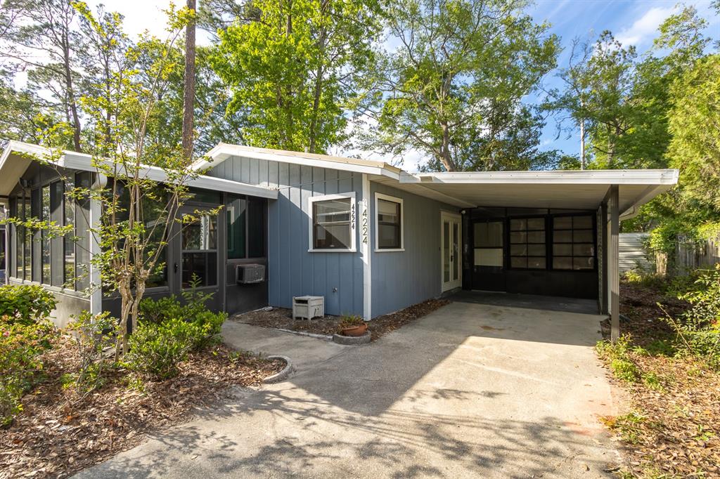 A blue single-story house features a screened-in porch, a carport, and a concrete driveway — 4224 NW 87TH LANE, GAINESVILLE, FL