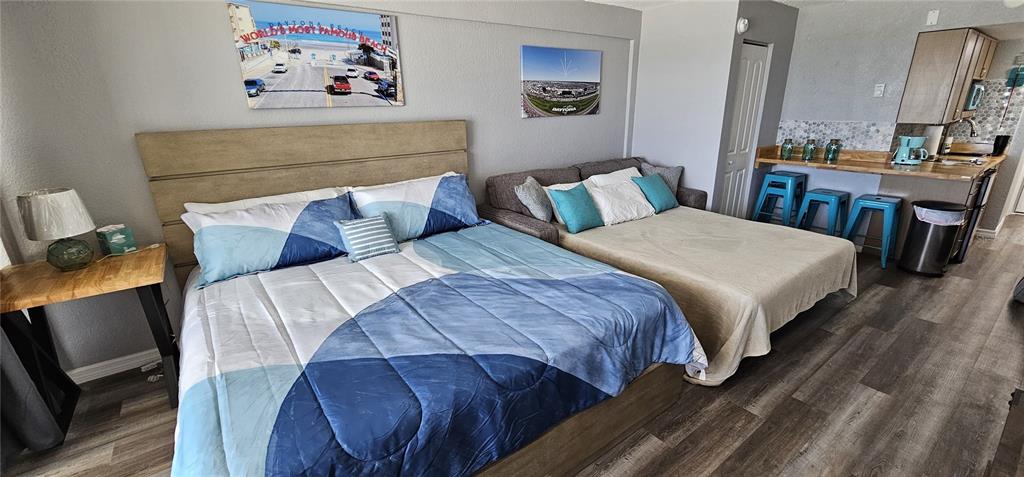 A bedroom features a bed, a pull-out sofa, and a small kitchenette with bar seating — 219 S ATLANTIC AVENUE UNIT 412, DAYTONA BEACH, FL