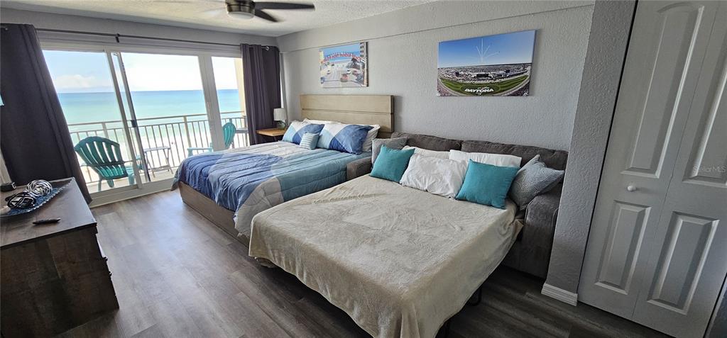 A bedroom features a bed, a pull-out sofa, and a balcony overlooking the ocean — 219 S ATLANTIC AVENUE UNIT 412, DAYTONA BEACH, FL