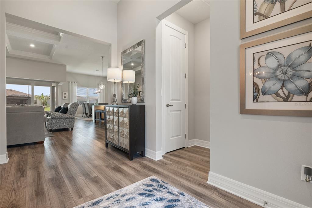 A bright entryway features wood-look flooring, a mirrored console table, and a white interior door — 4792 MARITIME WATERS COURT, LAND O LAKES, FL