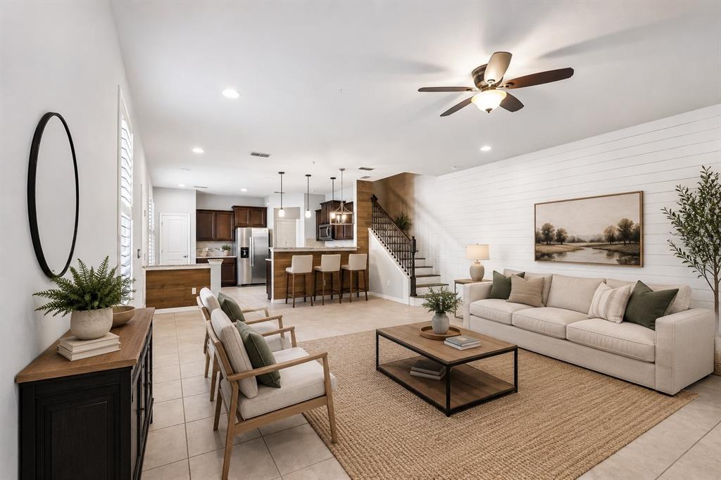 An open-concept living room and kitchen featuring a shiplap wall, staircase, and neutral furniture — 1164 PAVIA DRIVE, APOPKA, FL