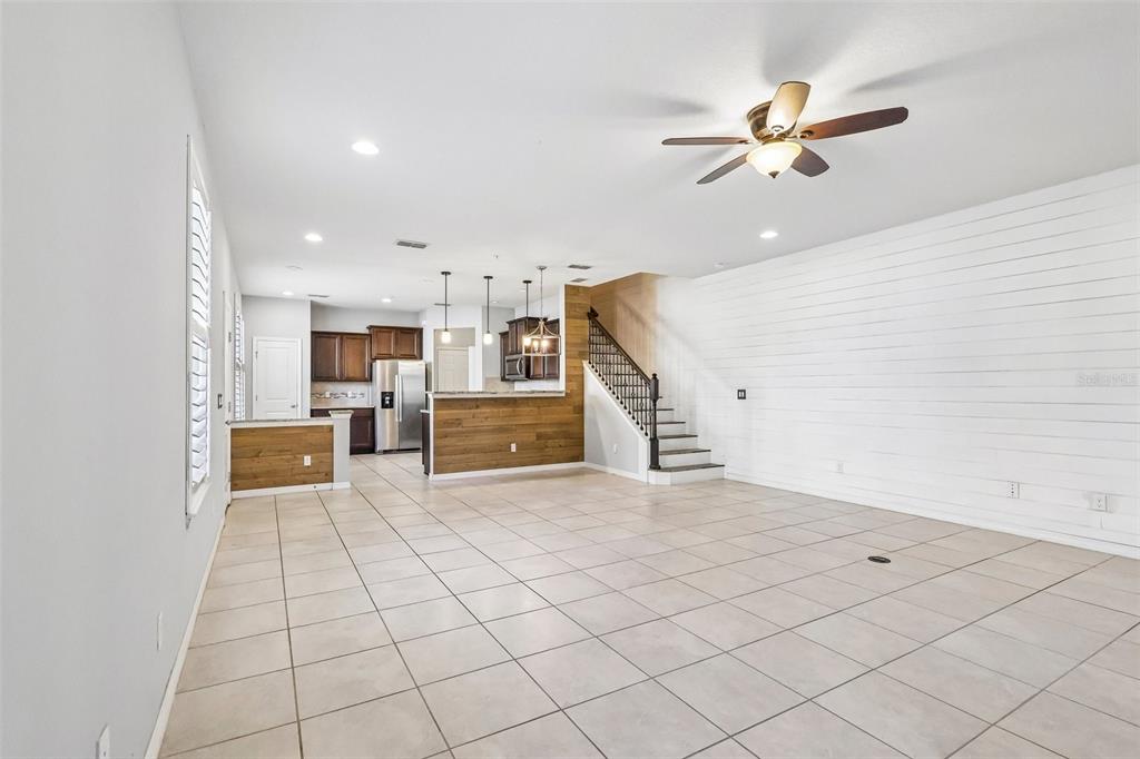 An open-concept living area features tile flooring, a wood-paneled kitchen island, and a staircase — 1164 PAVIA DRIVE, APOPKA, FL