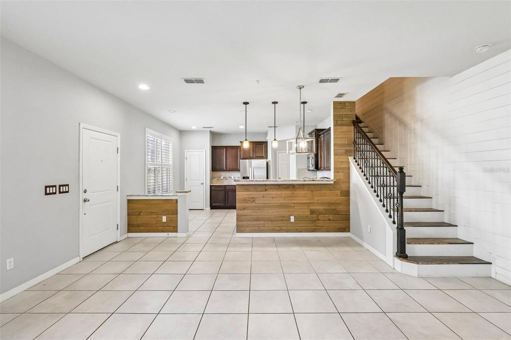 An open-concept living area features tile flooring, a wood-paneled kitchen island, and a staircase — 1164 PAVIA DRIVE, APOPKA, FL