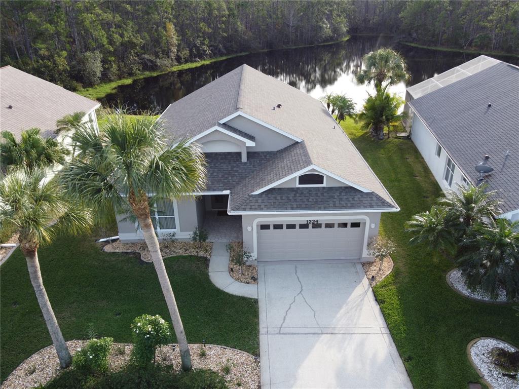 An aerial view shows a suburban house with a gray roof, garage, and palm trees — 1224 SIESTA KEY CIRCLE, PORT ORANGE, FL