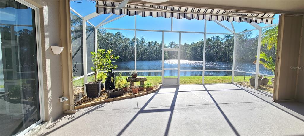 A screened-in patio overlooks a lake and forest with a concrete floor and awning — 1224 SIESTA KEY CIRCLE, PORT ORANGE, FL