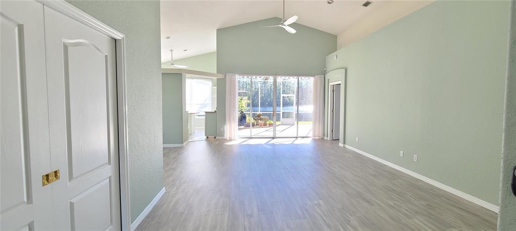 A spacious living area with light green walls, wood-look flooring, and large sliding glass doors — 1224 SIESTA KEY CIRCLE, PORT ORANGE, FL