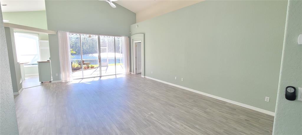 A spacious living room features light green walls, wood-look tile flooring, and sliding glass doors — 1224 SIESTA KEY CIRCLE, PORT ORANGE, FL